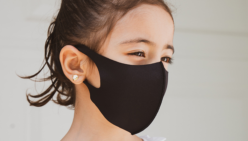 Young girl with brown hair wearing black mask